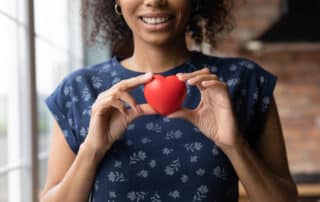 Happy African American volunteer girl holding red heart
