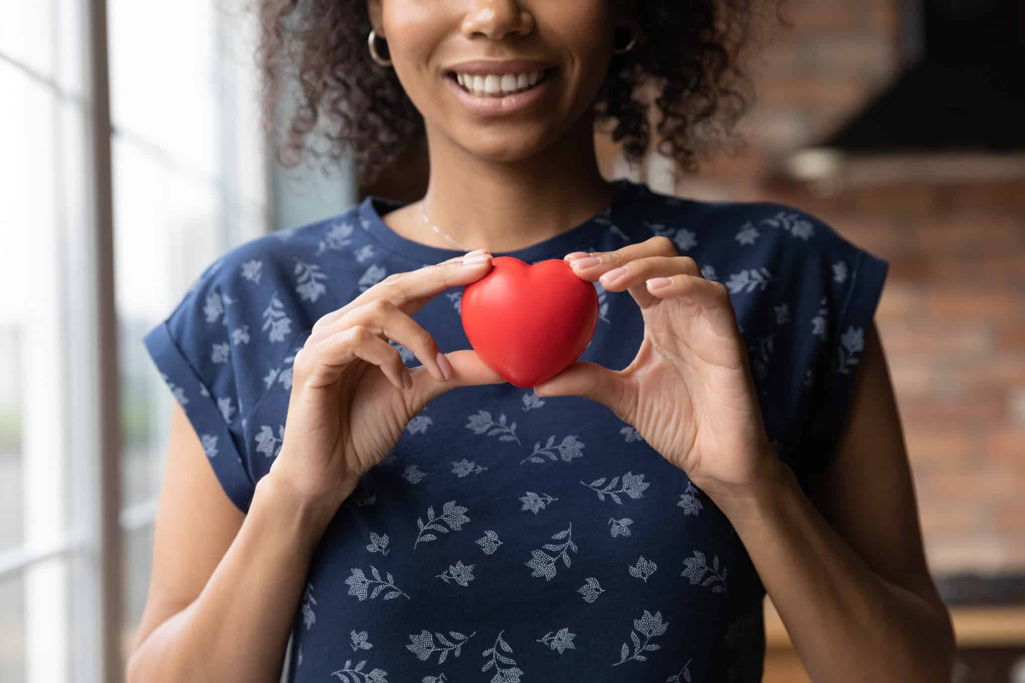 Happy African American volunteer girl holding red heart